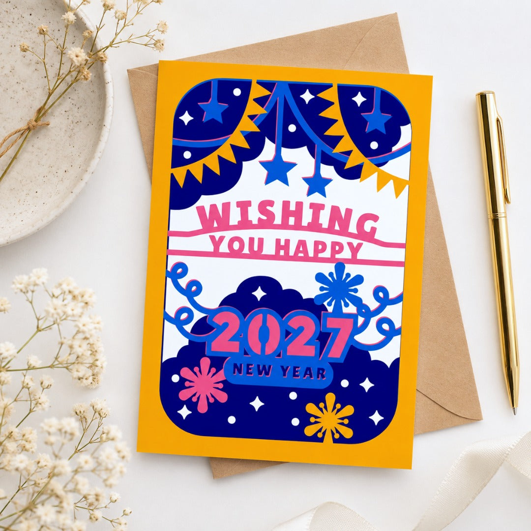 Flat lay mockup of a colorful 2027 New Year greeting card with kraft envelope, gold pen, and floral stationery styling.