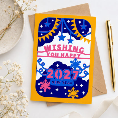 Flat lay mockup of a colorful 2027 New Year greeting card with kraft envelope, gold pen, and floral stationery styling.
