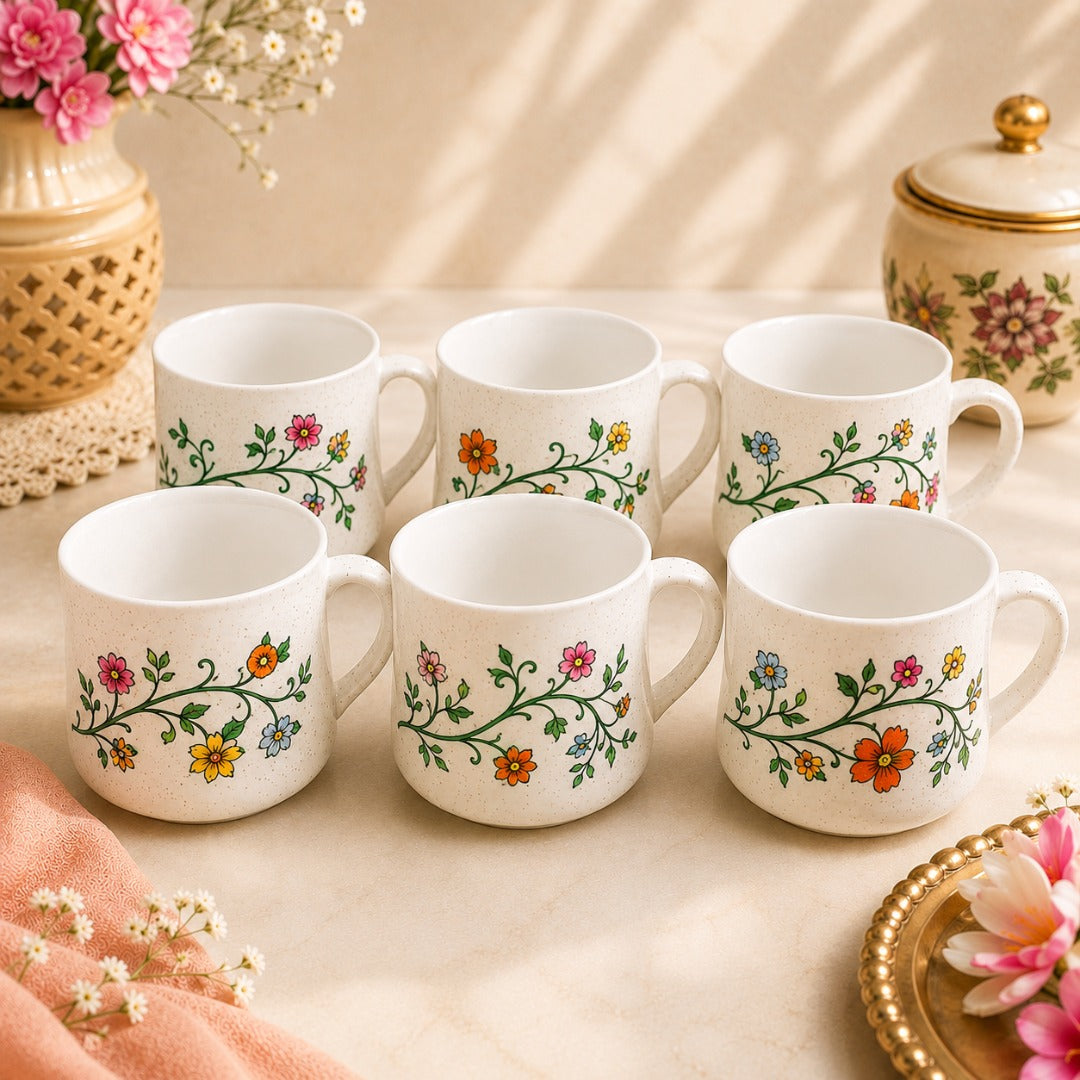 Ahaeli Set of six white ceramic tea cups with hand-painted floral vine design, arranged on an elegant cream tabletop with soft floral décor.