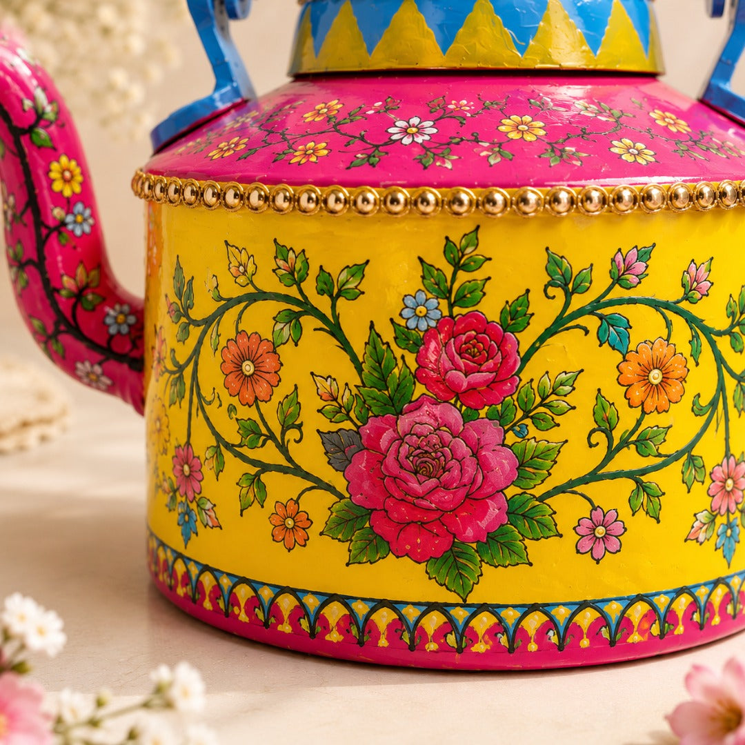 Close-up of a ahaeli handcrafted floral teapot featuring pink roses, colorful flowers, and intricate folk art detailing on a bright yellow body.
