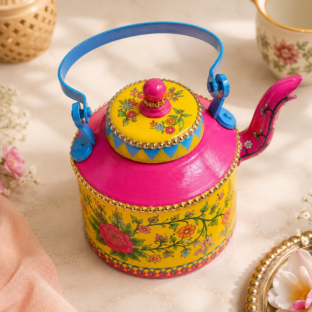 Aaeli Top-angle view of a vibrant hand-painted floral yellow and pink teapot with blue handle and intricate folk art details.