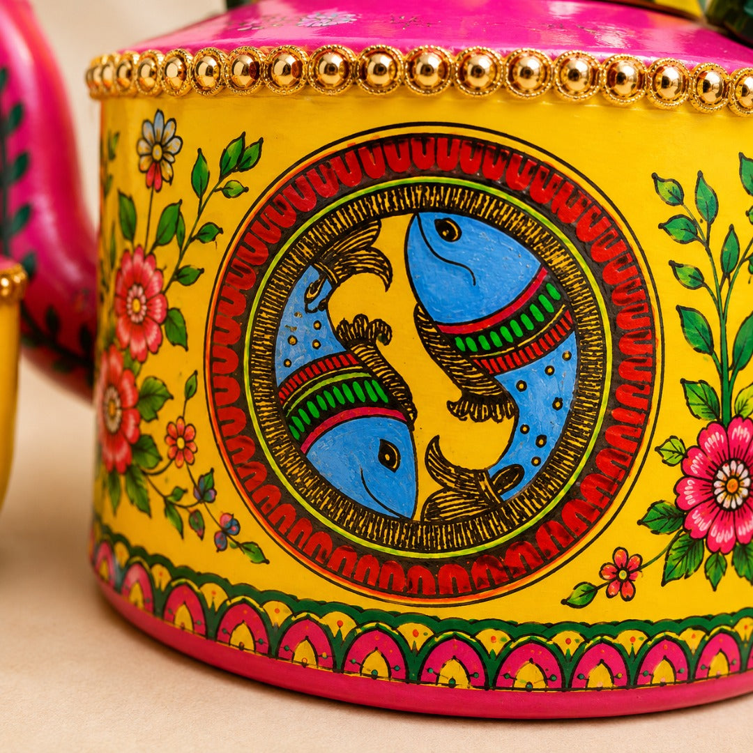 Close-up of Ahaeli handcrafted Madhubani hand-painted tea kettle featuring intricate floral folk art detailing in vibrant yellow and pink with premium artisan finish.