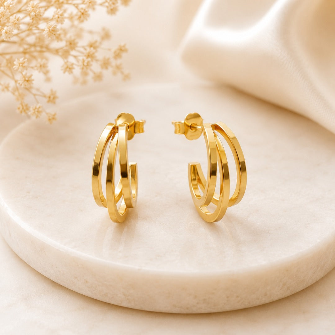 Angled view of elegant triple band gold hoop stud earrings for women with a sleek polished gold finish.