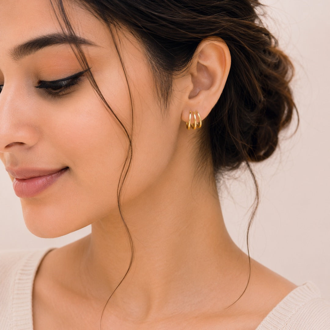 Woman wearing elegant triple band gold hoop stud earrings with a minimal everyday style.