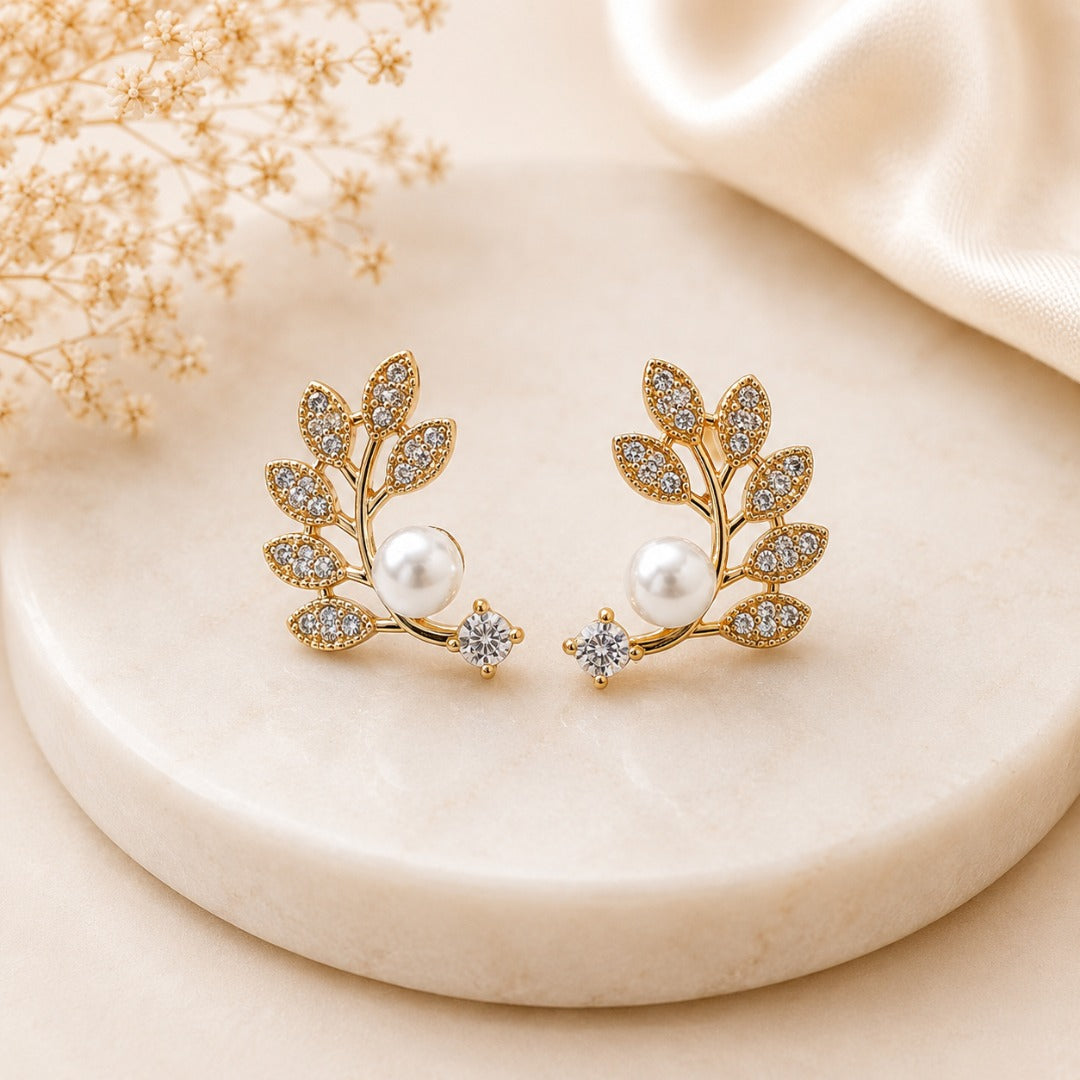 Gold leaf-inspired pearl stud earrings for women with cubic zirconia accents.