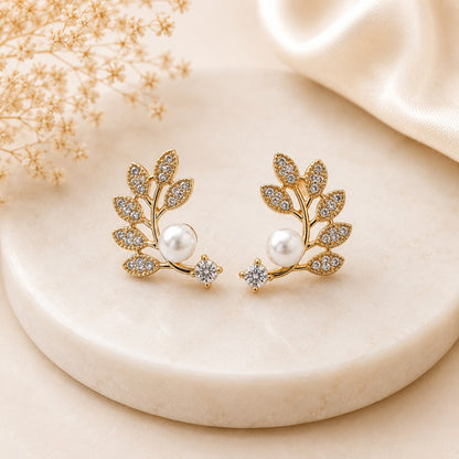 Gold leaf-inspired pearl stud earrings for women with cubic zirconia accents.