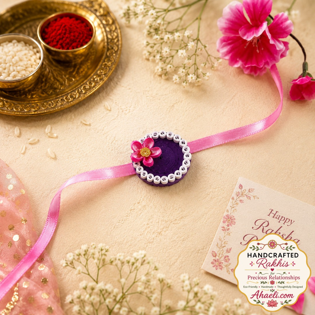 Handmade paper quilled pink blossom rakhi with pink flower and purple base for Raksha Bandhan.