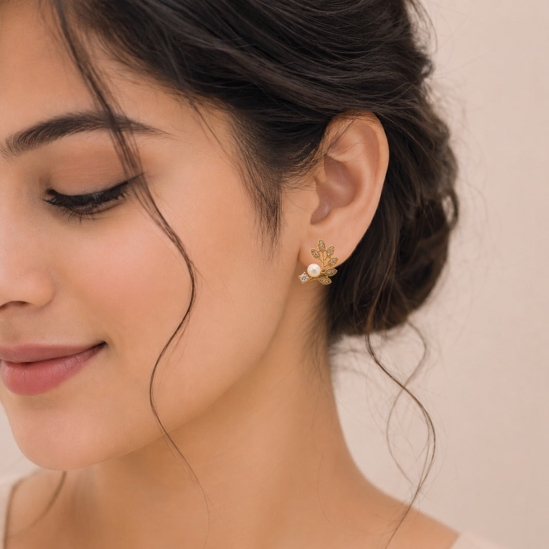 Woman wearing elegant gold pearl leaf stud earrings for a timeless everyday look.