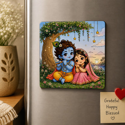 Radha Krishna Fridge Magnet featuring a cute illustration of Lord Krishna playing the flute beside Radha in a peaceful garden setting with divine love artwork.