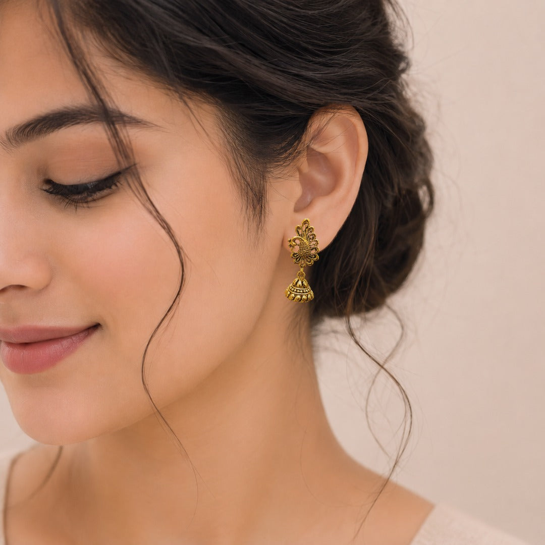 Woman wearing traditional peacock floral jhumka earrings in antique gold finish